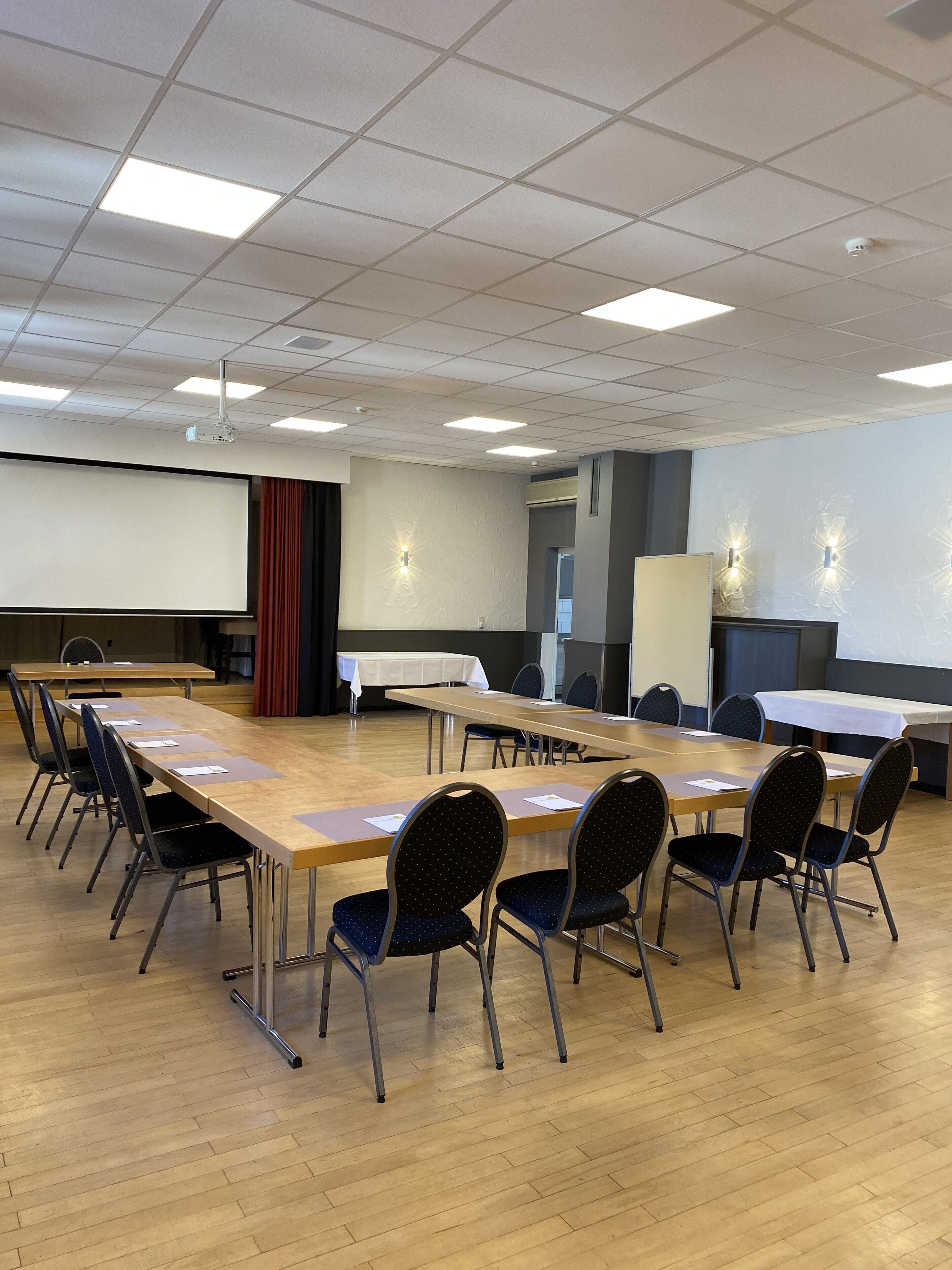 Ein Konferenzraum mit einem langen Tisch, Stühlen, einem Projektor und einer Leinwand.