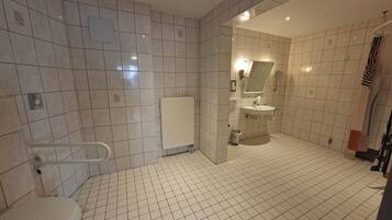 Een badkamer met toilet, radiator, wastafel en douche.