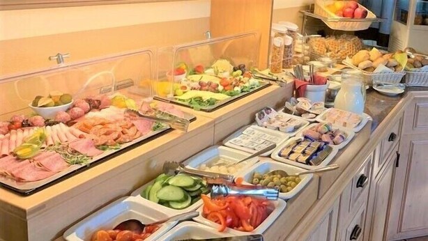 Un bufé con diversas opciones de comida, incluyendo carnes, quesos, frutas y verduras.