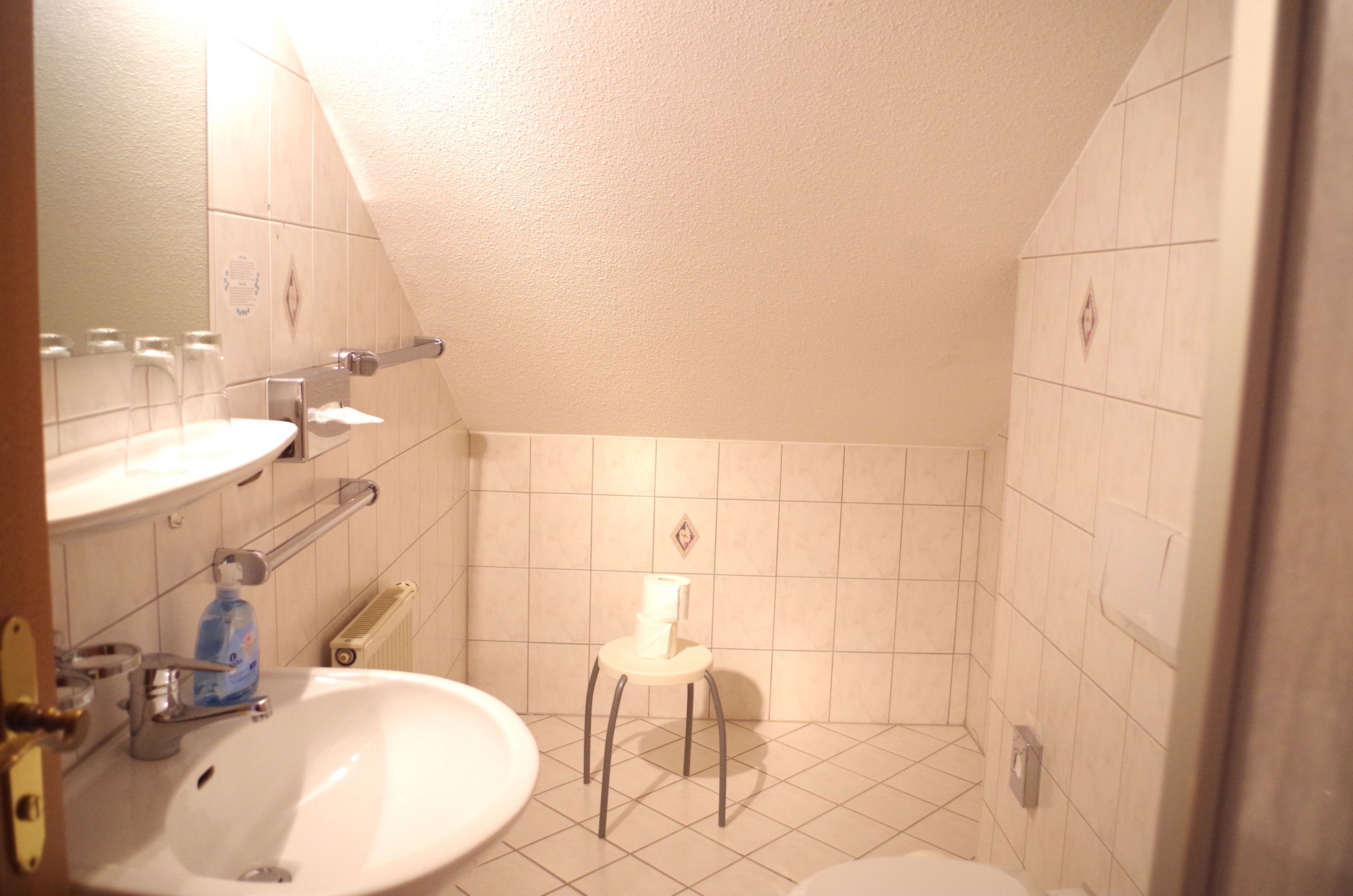 Un baño pequeño con lavamanos, espejo e inodoro.