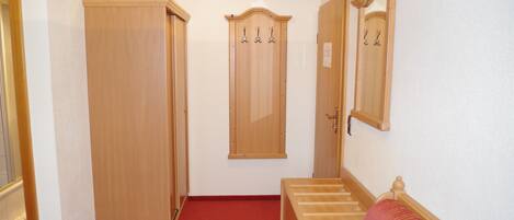 A hallway with wooden doors, a red carpet, and a wooden bench.