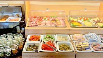 Un bufé con diversas opciones de comida, incluyendo carnes, quesos y verduras.