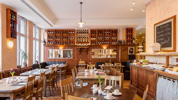 Un restaurante con mesas y sillas de madera, una alacena para vinos y un menú en una pizarra.