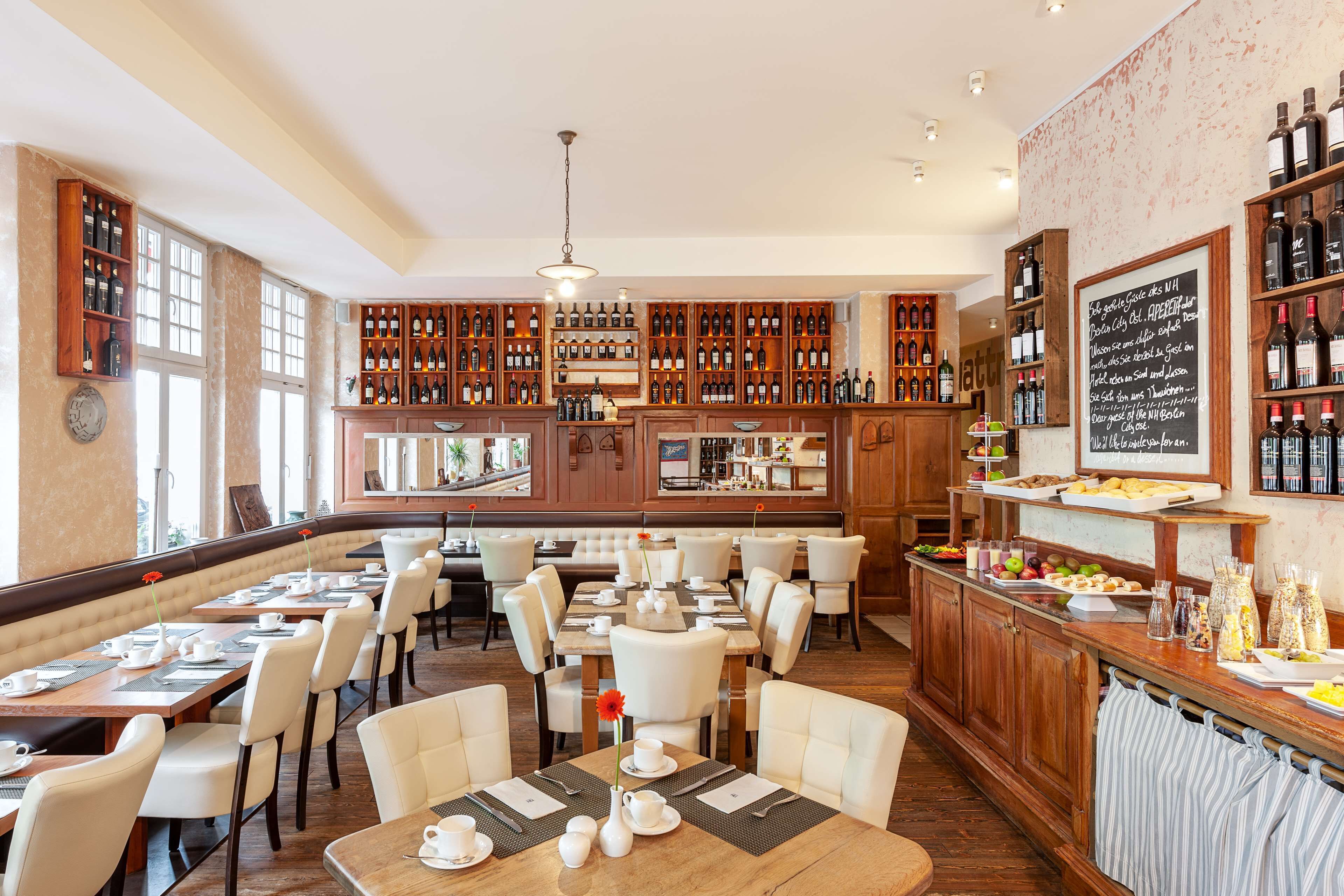 Un restaurante con varias mesas, una zona de bar con botellas de vino y un menú en la pizarra.