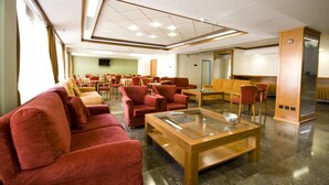 A spacious lobby with red sofas, a glass coffee table, and a modern ceiling design. - Diana Hotel (Chios)