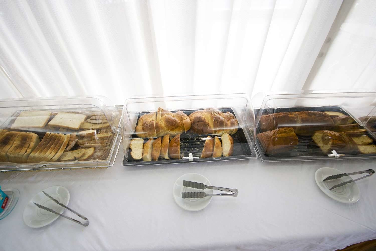 Three glass display cases with various types of bread and pastries on a table.