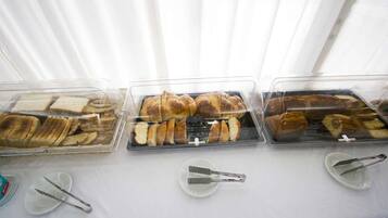 Three glass display cases with various types of bread and pastries on a table.