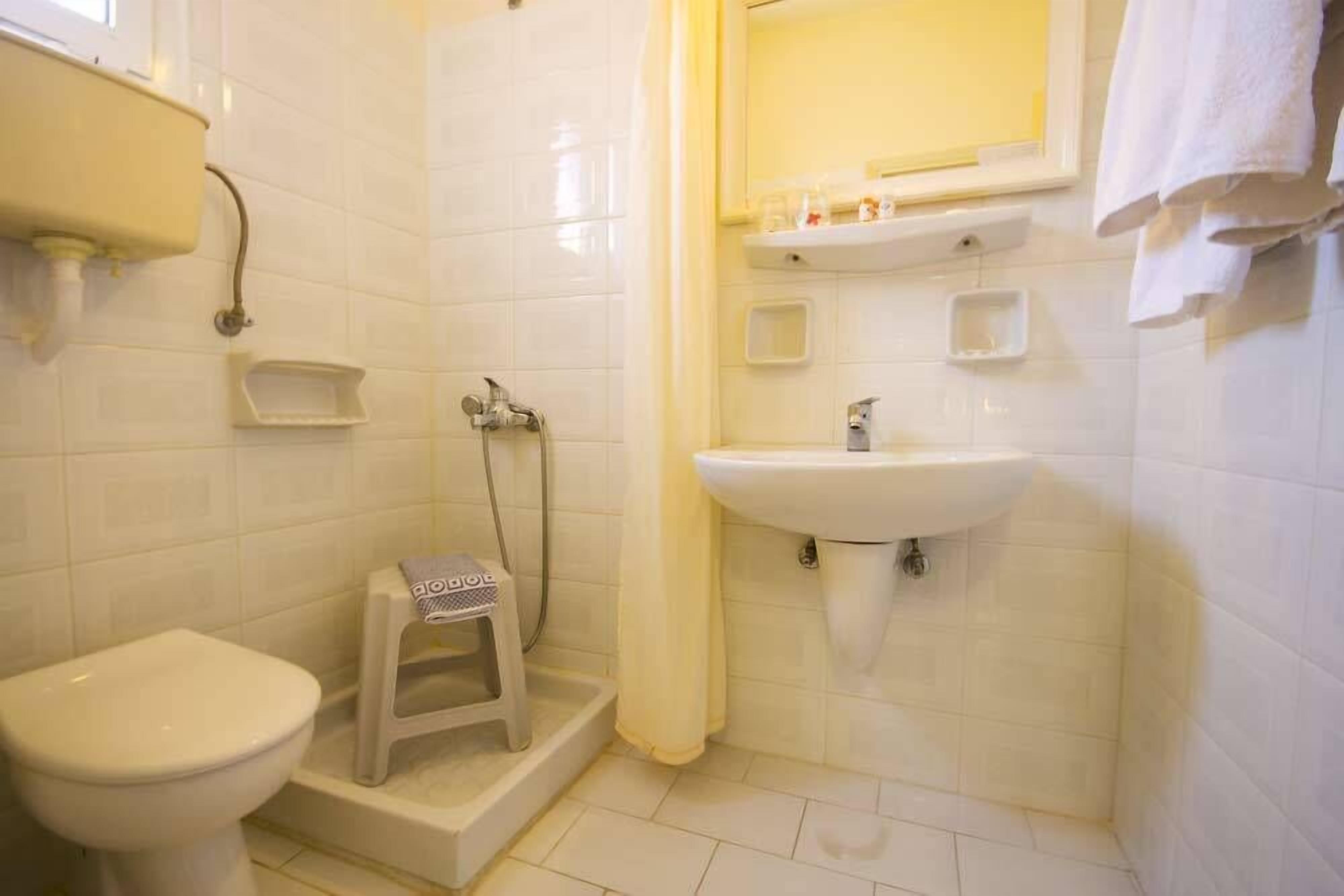 Un baño pequeño con inodoro, lavamanos y ducha.