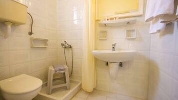 Un baño pequeño con inodoro, lavamanos y ducha.