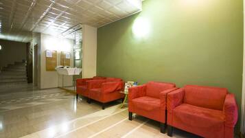A reception area with a check-in counter, two red sofas, and a staircase in the background.