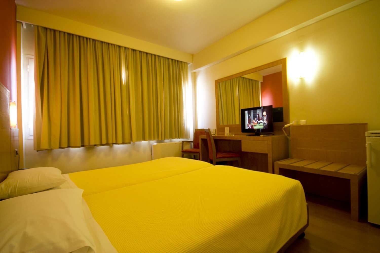 Una habitación de hotel con una cama grande, un escritorio, un televisor y un espejo.