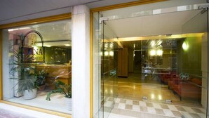 A hotel entrance with a reception desk, potted plants, and a check-in area visible through the glass doors. - Diana Hotel (Chios)
