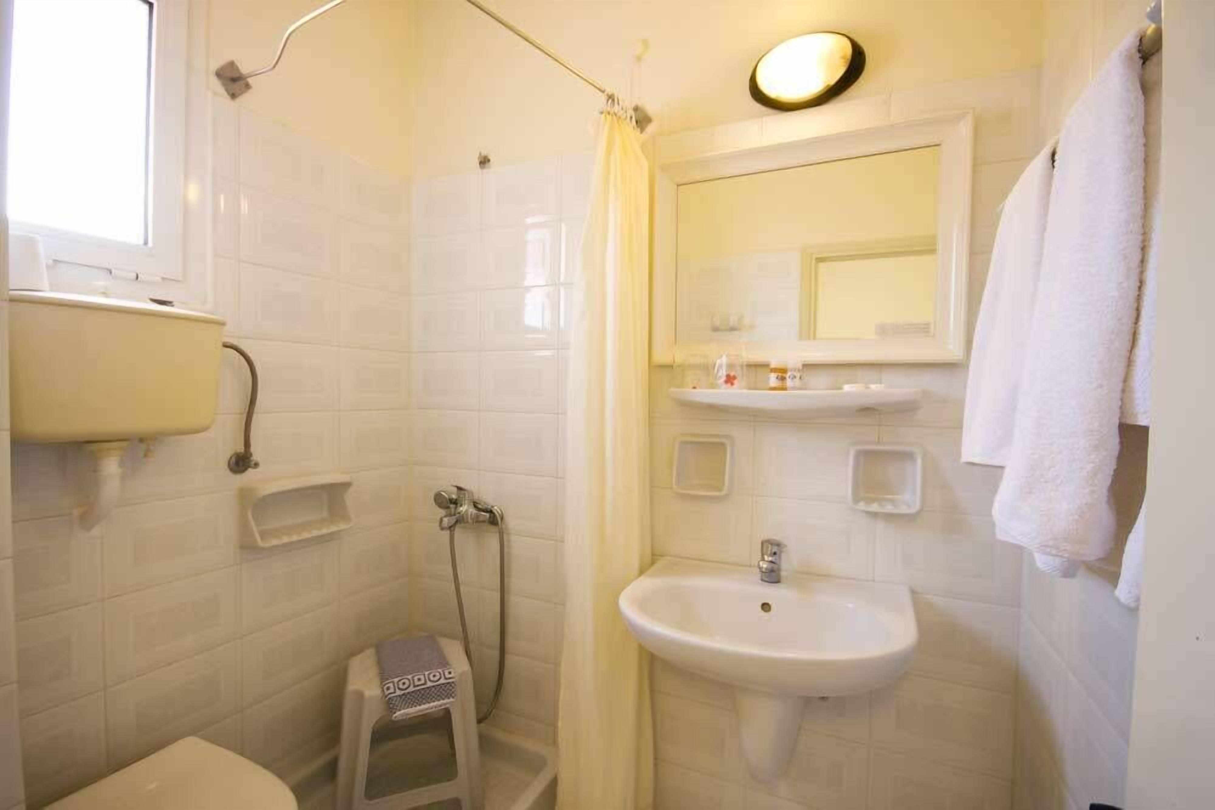 Un baño con inodoro, lavamanos, ducha y espejo.