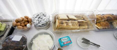 A buffet table with various food items including eggs, bread, and cheese.