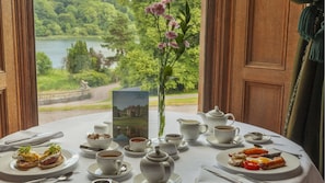 A table set for breakfast with a scenic view of a lake and greenery.