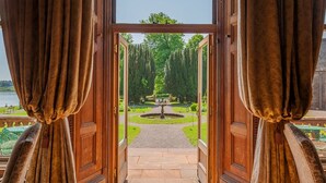Vista a través de una puerta de madera que da a un jardín con una fuente y un camino.