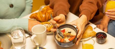 A breakfast setting with croissants, a bowl of soup, and a glass of orange juice.