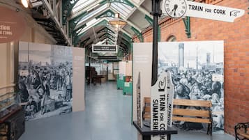 Interior de una estación de tren histórica con paneles informativos y un reloj.