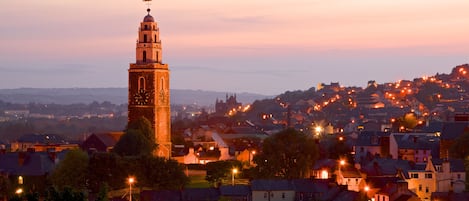A historic tower with a clock, surrounded by residential buildings and streetlights, indicating a town setting.