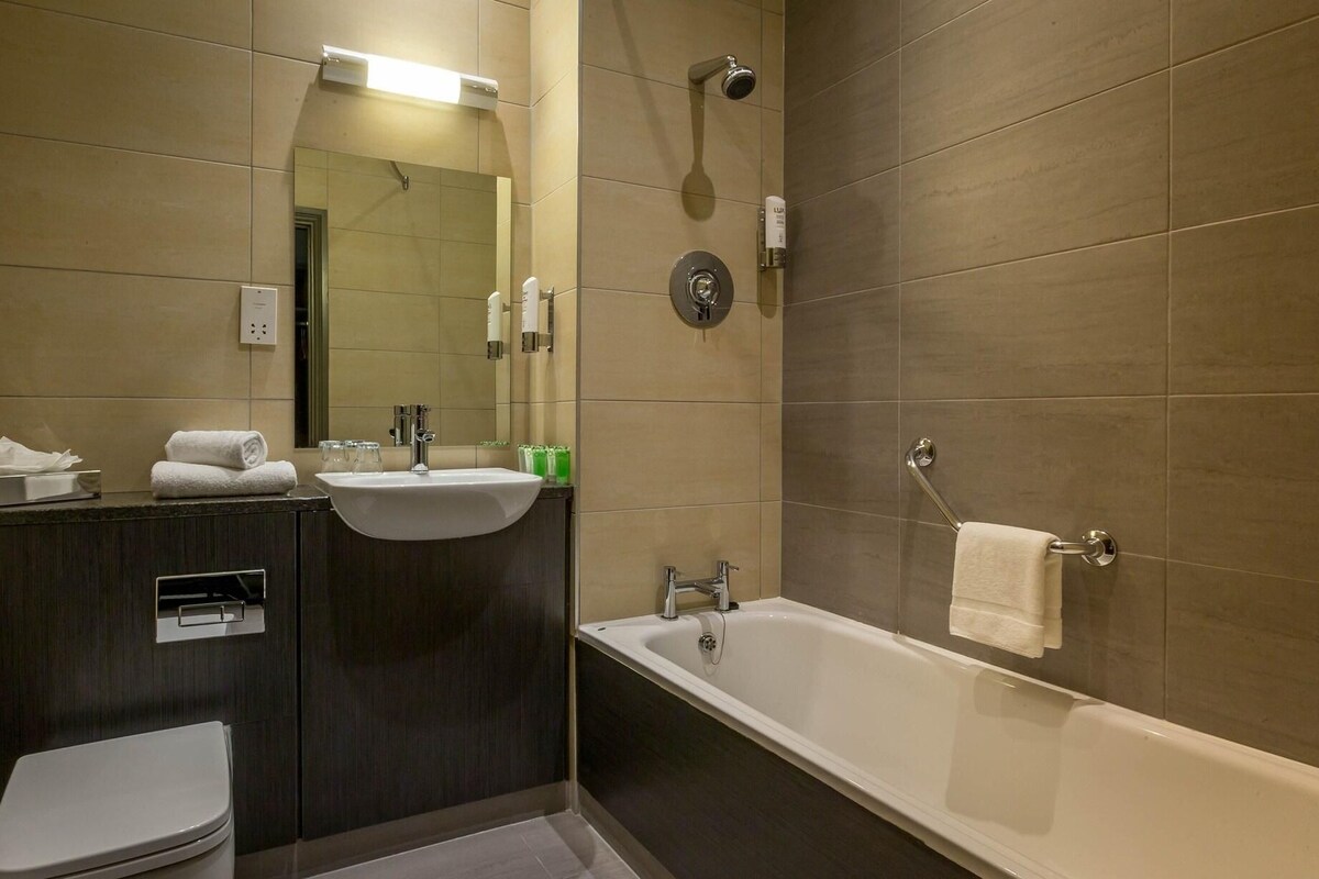 A modern bathroom with a toilet, sink, and bathtub.