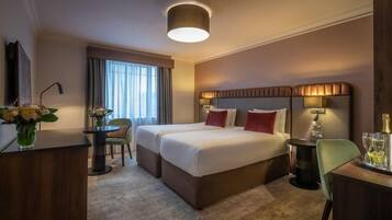 Habitación de hotel con cama doble, un escritorio, una silla y una pequeña mesa con un florero.