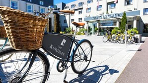 Ein Fahrrad mit Korbrad und einem Schild mit der Aufschrift "The Kingsley" vor einem Hotel.