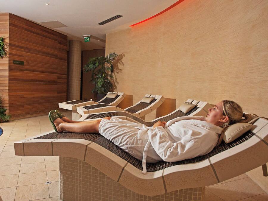 Une salle de spa avec des fauteuils inclinables, un mur en bois et une plante en pot.