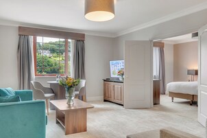 Una habitación de hotel moderna con un ventanal grande, una zona de comedor, una cama y un televisor.
