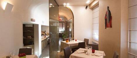 Un restaurante con mesas dispuestas para comer, una zona de cocina al fondo y una decoración de diseño moderno.