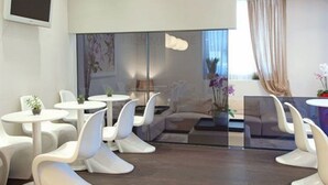 Een moderne hotelkamer met witte meubels, een groot raam met gordijnen en uitzicht op de stad.