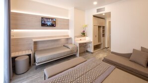 Een moderne hotelkamer met een bed, een bank, een bureau en een aan de muur bevestigde televisie.
