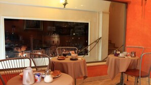Un comedor con dos mesas redondas, sillas y vistas a un paisaje urbano a través de un ventanal amplio.