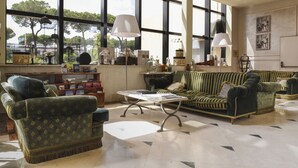 A spacious living room with large windows, a sofa set, and a coffee table. - Hotel Leon d'Oro (Verona)