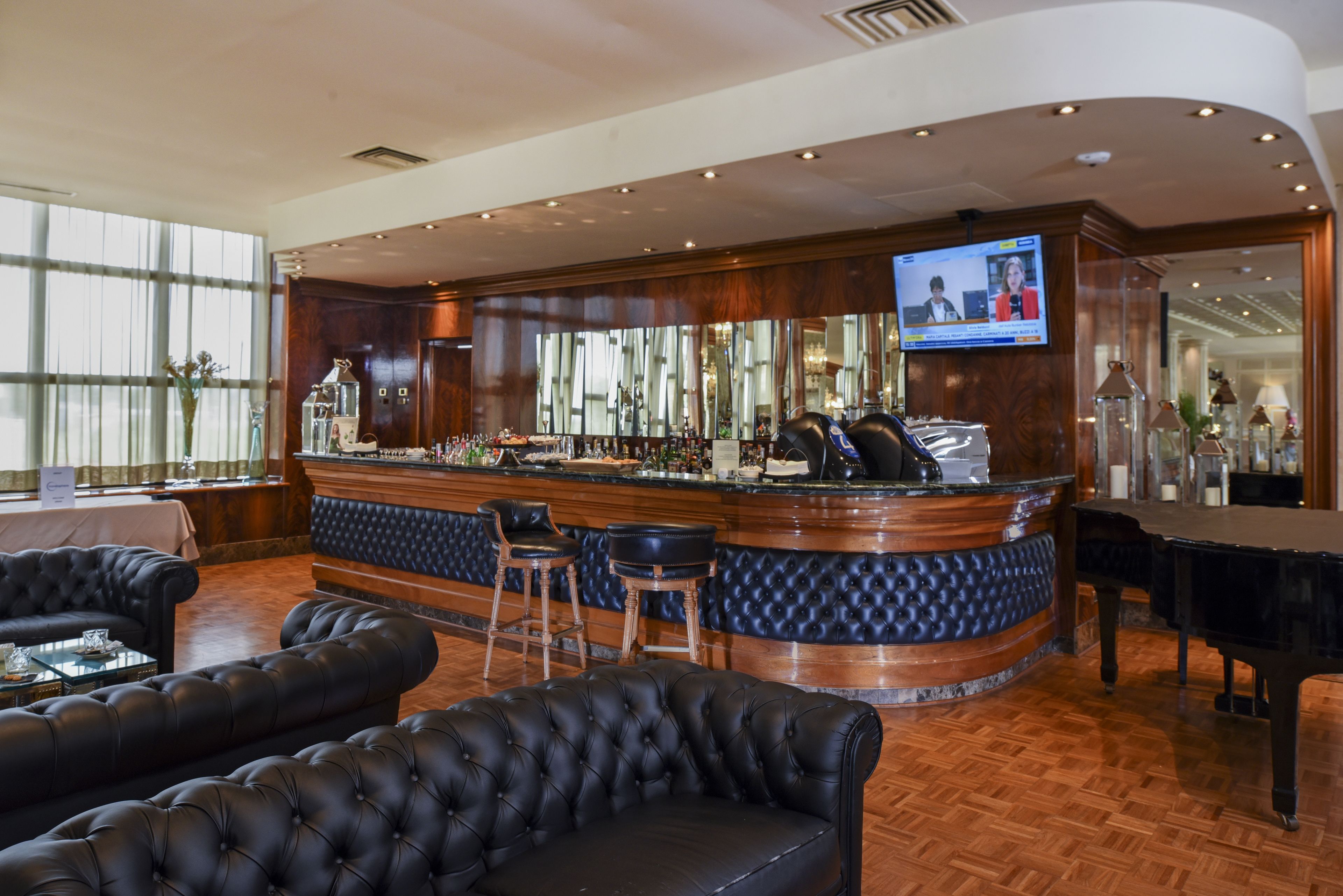 A bar area with a wooden counter, leather seating, and a television screen.