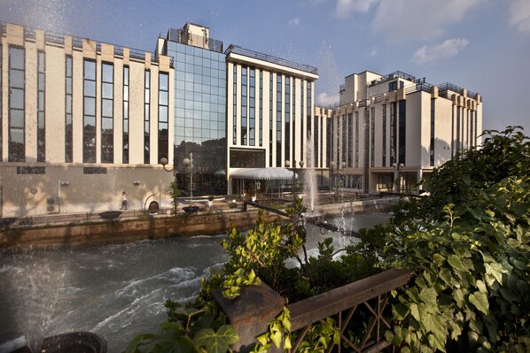 A modern building with large windows and a water feature in front.