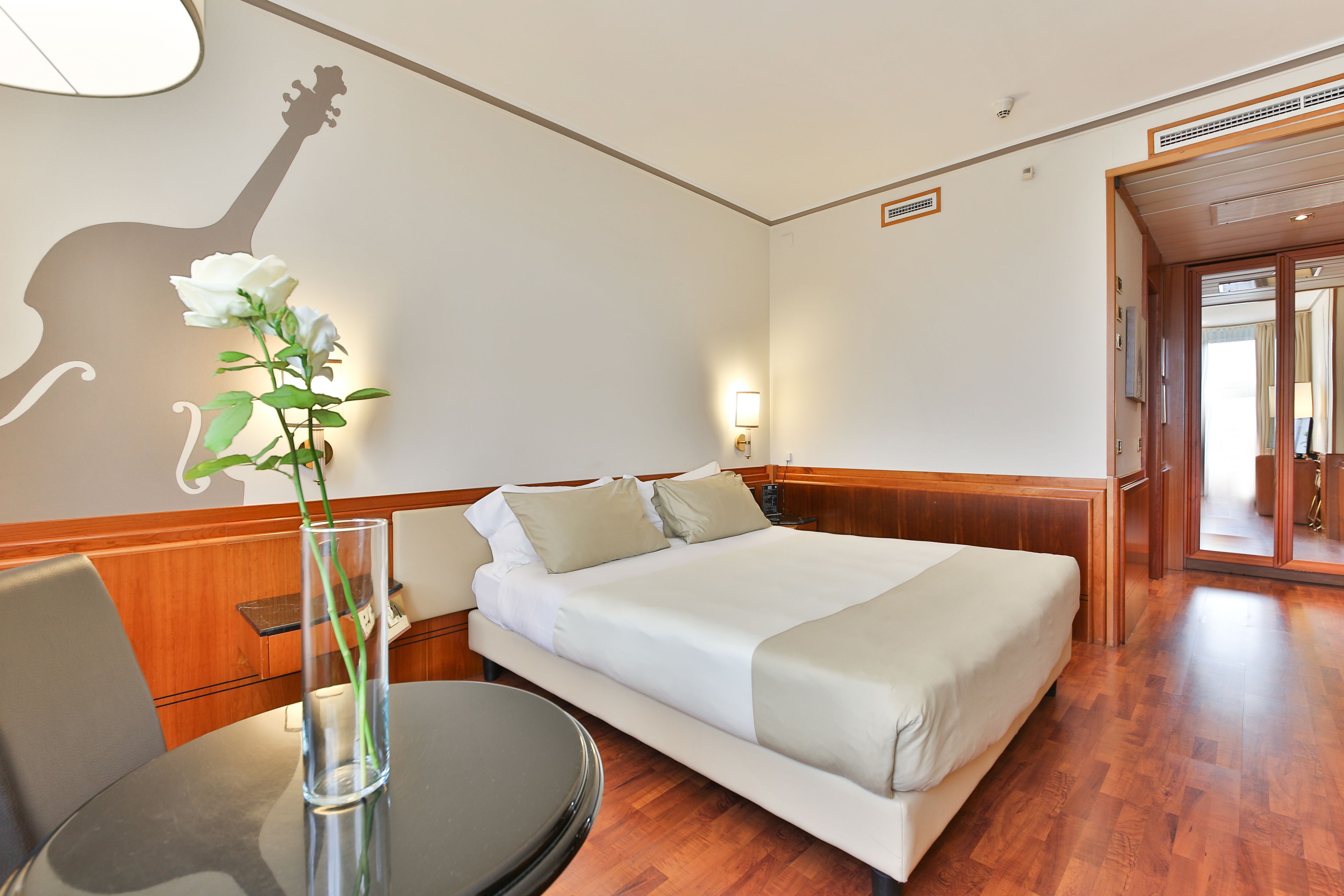 A hotel room with a bed, bedside table, and a wall decoration of a giraffe silhouette.