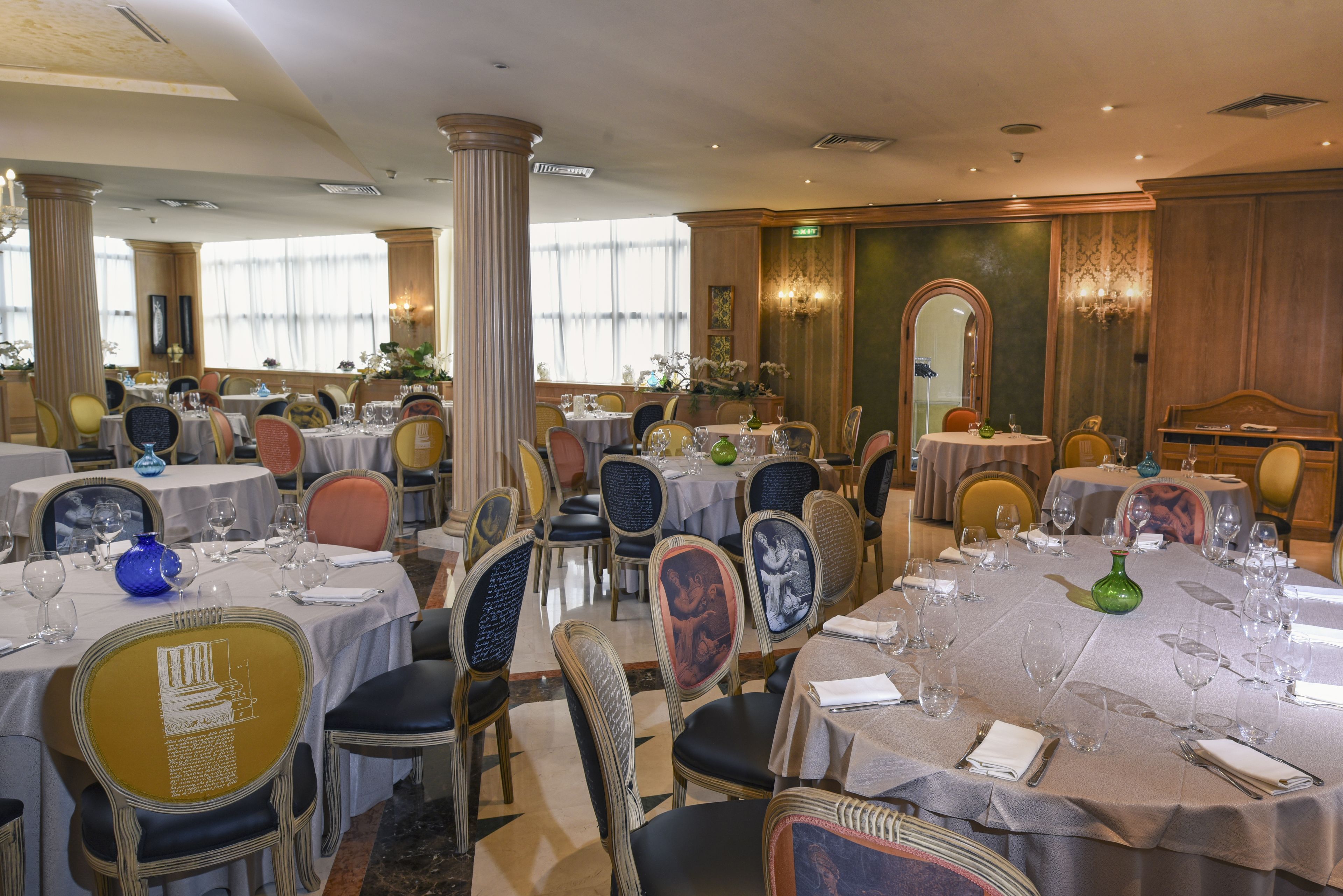 A restaurant with round tables, chairs, and a chandelier.