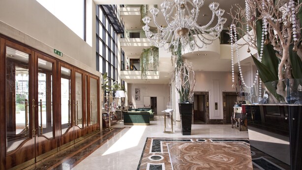 A spacious lobby with a marble floor, a grand chandelier, and a large wooden reception desk. - Hotel Leon d'Oro (Verona)