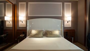 Una habitación de hotel con una cama grande, dos lámparas de noche, un teléfono y un espejo.