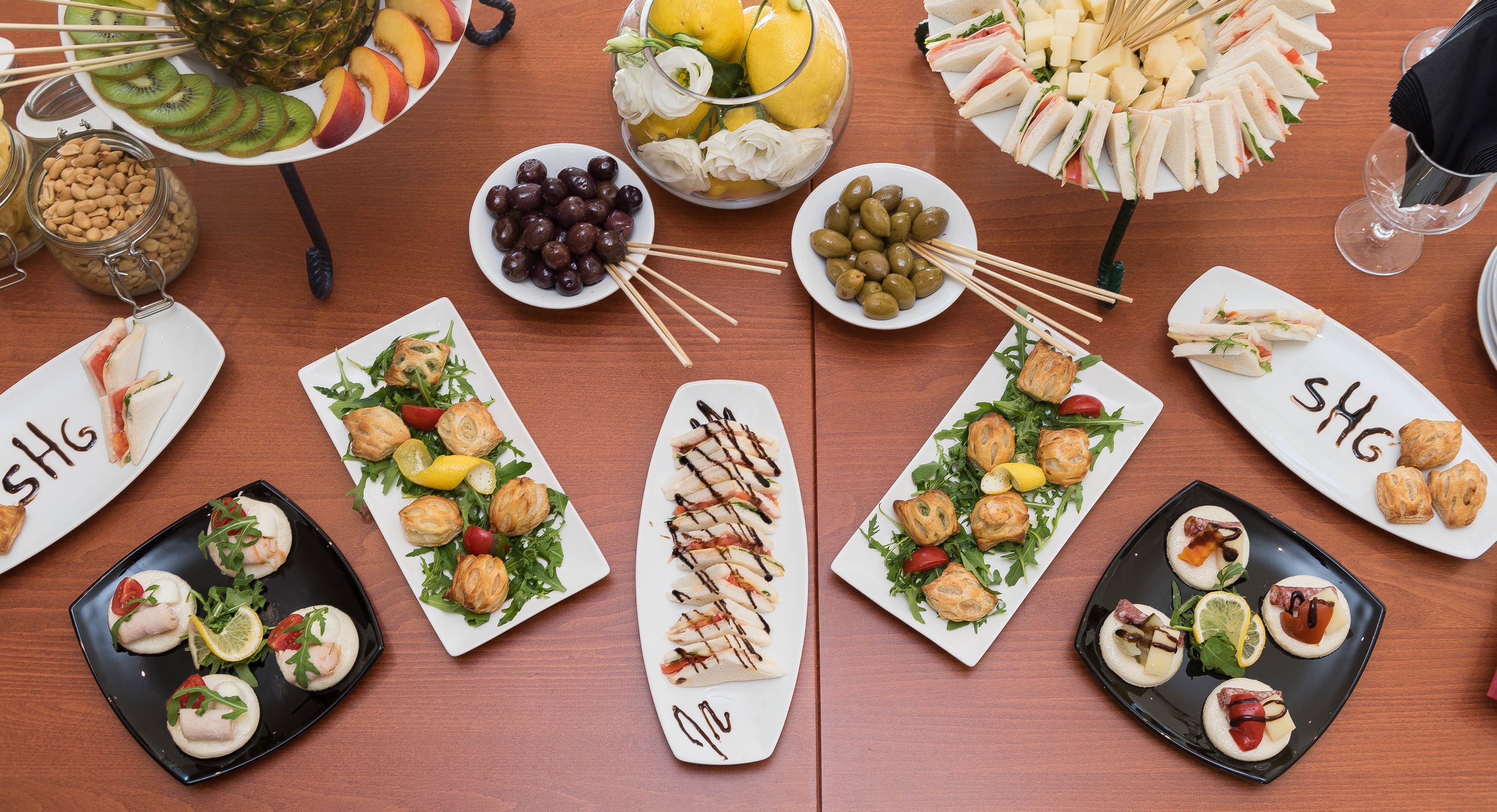 Una mesa con diversos alimentos, como sándwiches, frutas y aperitivos.