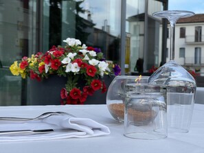 A table set with a wine glass, two water glasses, a bowl of nuts, and a bouquet of colorful flowers.
