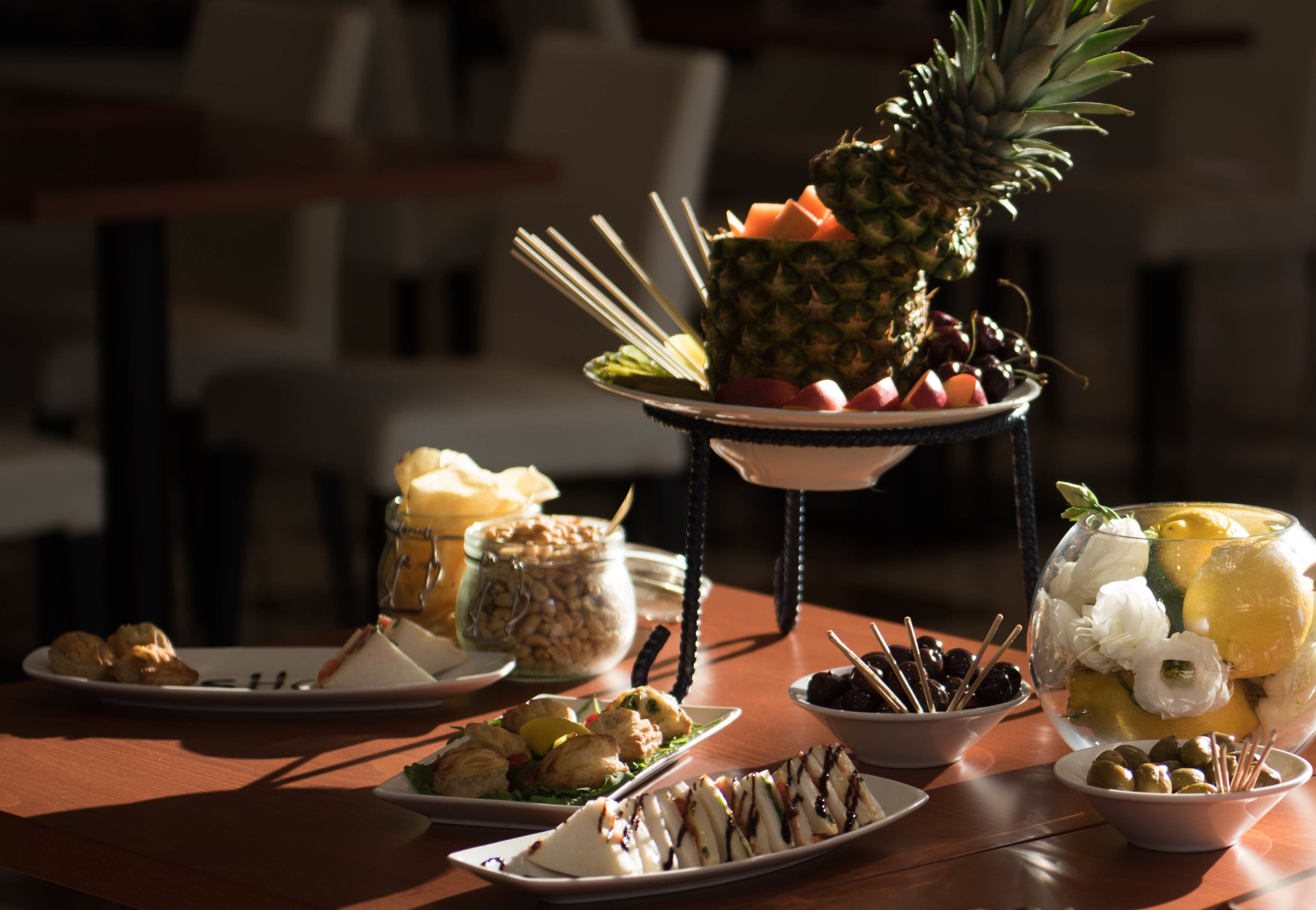 Una mesa con diversos alimentos, incluyendo una piña, queso y aceitunas.