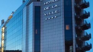 Ein modernes Hotelgebäude mit einer gläsernen Fassade und einem Schild mit der Aufschrift "HOTEL DE LA VILLE".