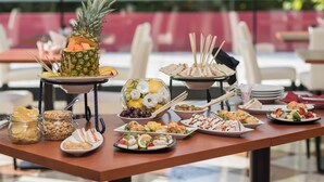 Ein reichhaltiges Buffet mit verschiedenen Speisen, darunter eine Ananas als Mittelstück, Salaten und Snacks.