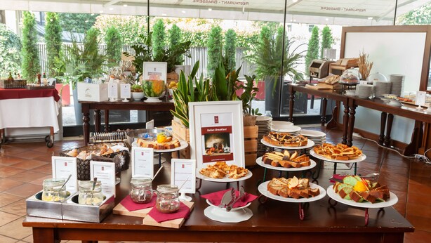 Ein reichhaltiges Buffet mit verschiedenen Speisen und einem Schild mit der Aufschrift 'Italienisches Frühstück'.
