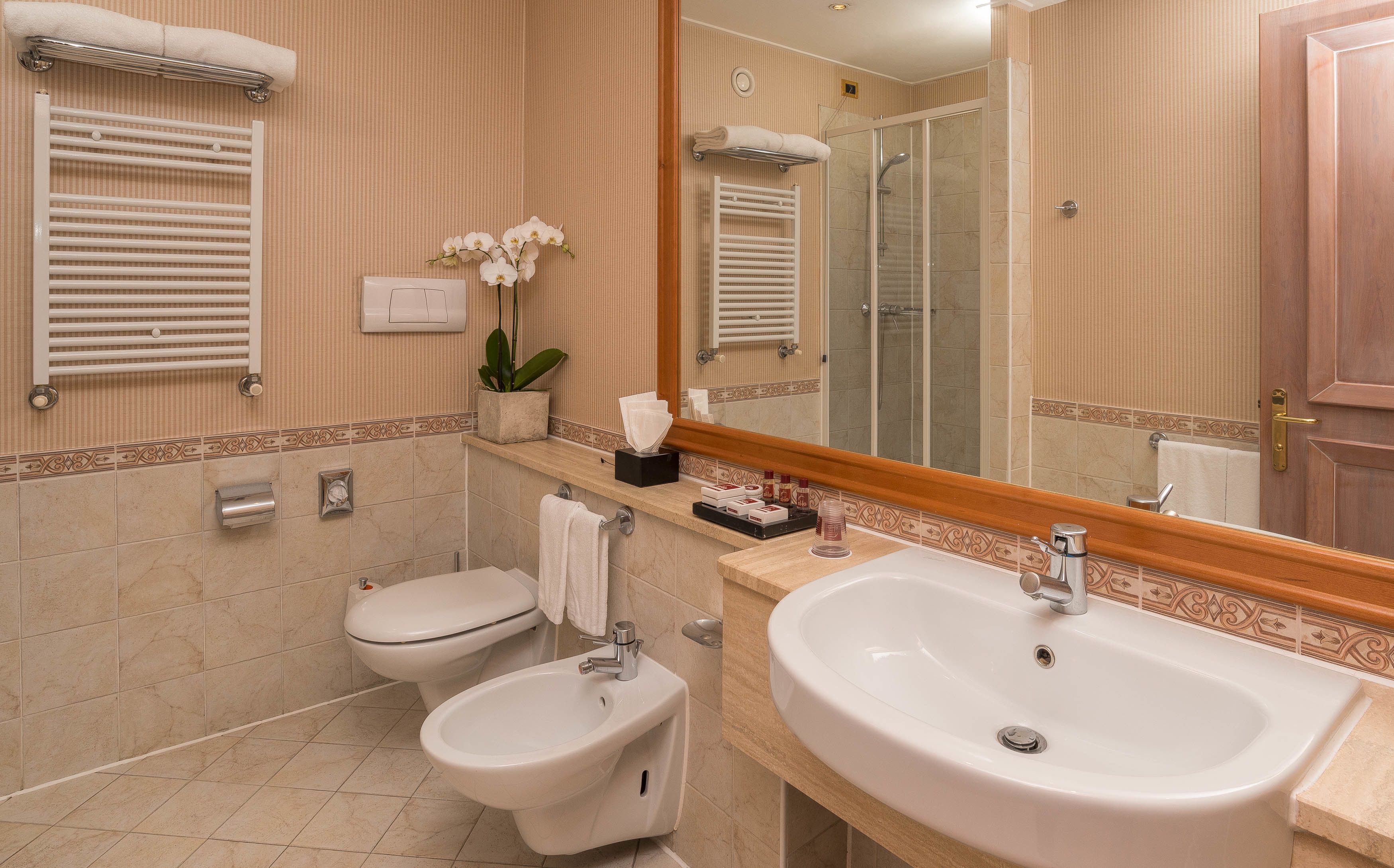 A bathroom with a sink, bidet, toilet, towel rack, and a mirror.