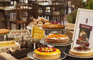 A variety of desserts and pastries on display, including cakes, tarts, and pastries, with a sign indicating an Italian breakfast option.