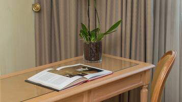 A wooden table with a glass top, a book, and a vase with white orchids.