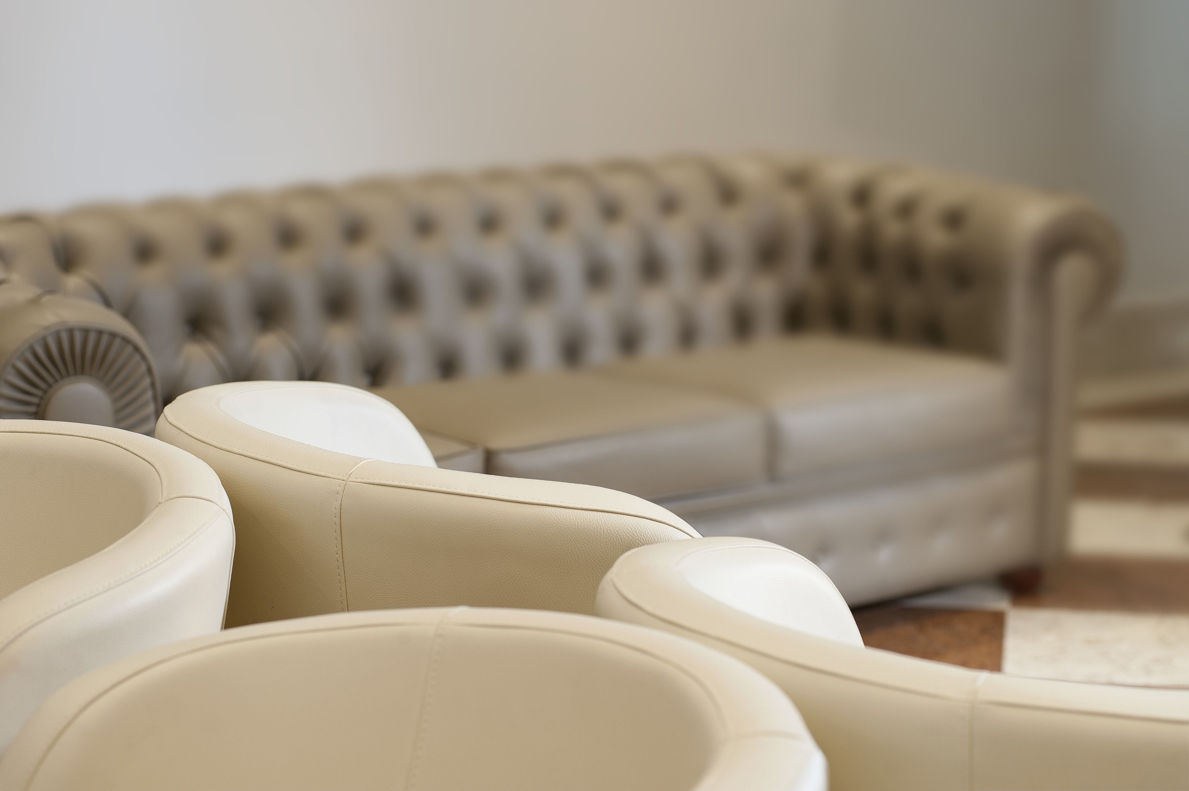 A beige sofa with a tufted backrest and a matching ottoman.