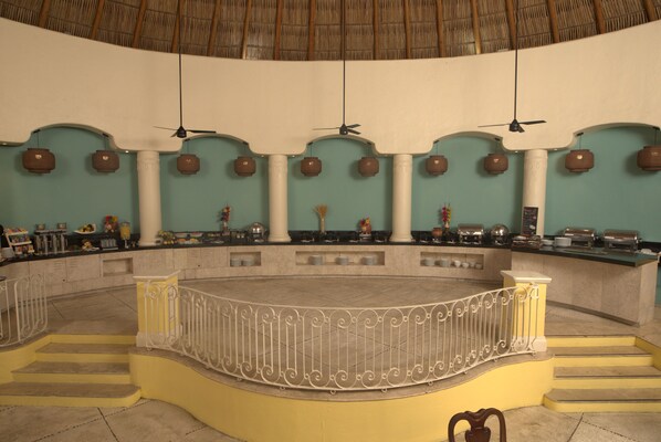 A spacious, curved bar area with a central railing, multiple ceiling fans, and a thatched roof.